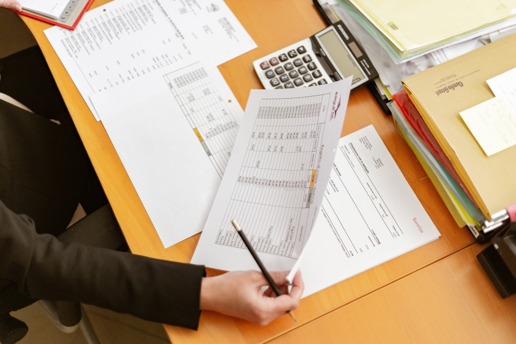 person holding white printer paper and pen 2058136